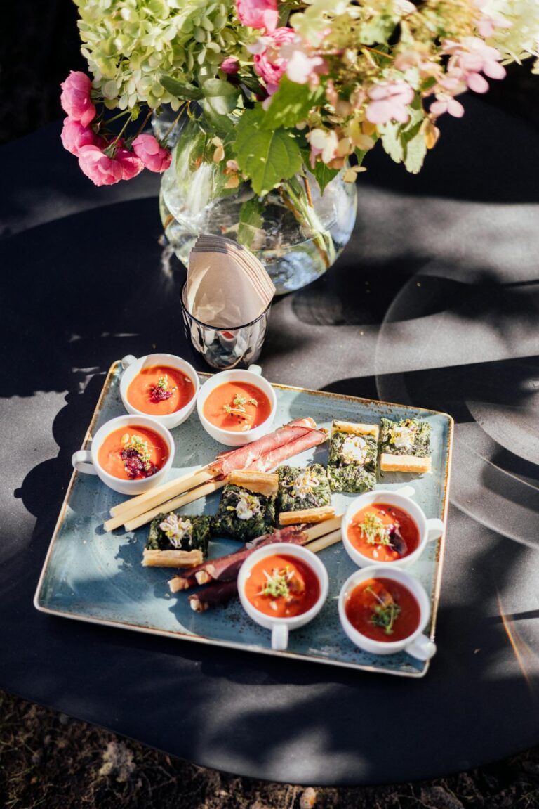 Gourmet appetizers beautifully arranged on a platter with a floral backdrop, perfect for special occasions.